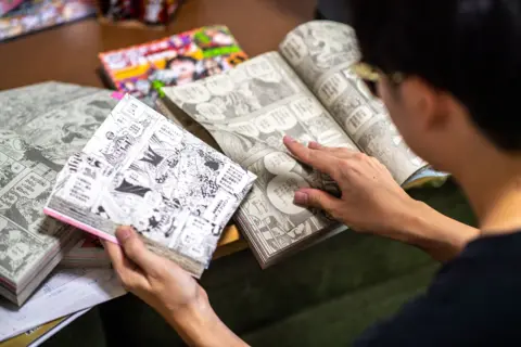 Getty A young Japanese boy reading multiple copies of the One Piece manga