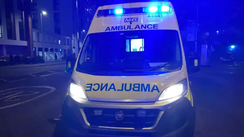 A generic picture of yellow ambulance parked on a road at night