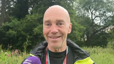Tony Chalk smiling while standing outside wearing a black and yellow coat