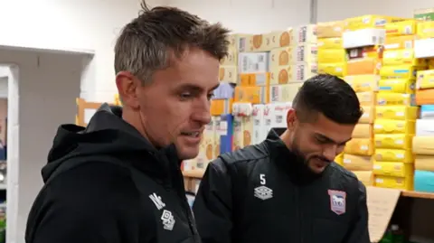 Alex Dunlop/BBC Kieran McKenna and Sam Morsy from Ipswich Town helping a Suffolk charity sort out food