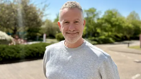 A man stood outside smiling into the camera