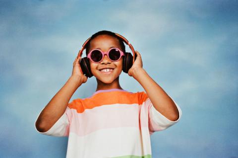 boy listening to music through headphones smiling while wearing sunglasses