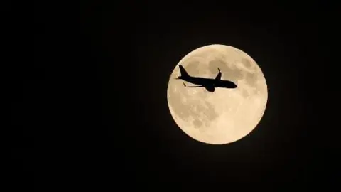 Bubs A silhouette of a plane crossing the supermoon.