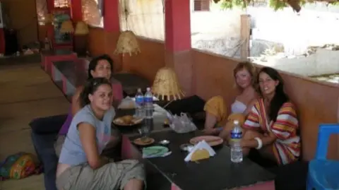 Lowri Denman Lowri eating with friends in India in 2007. Four girls sit around a table wearing summer clothing. 