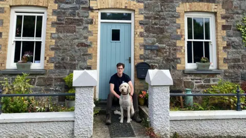 Sarah Browning Jack outside his mother's cottage with his dog