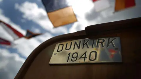 Getty Images A brass plate reading "DUNKIRK 1940" on the deck of a boat. In the background there are semaphore flags on bunting. 