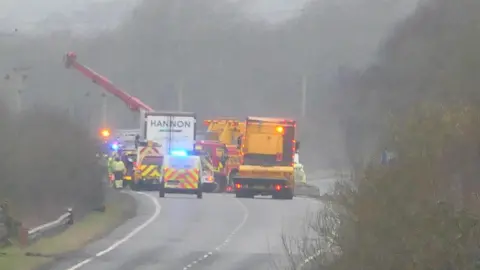 Billy Jardine Emergency service vehicles and lorries block a road. It is a wet day. A man in hi-vis can also be seen