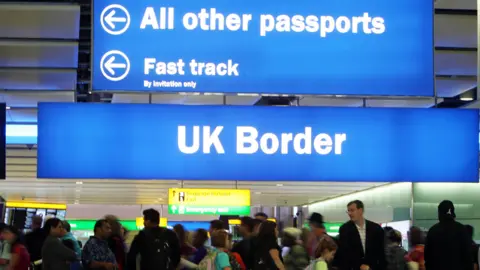 Queues of people at the UK border checks at an airport.