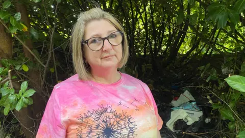 BBC Amanda with rubbish behind her