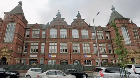 A large red-brick Victorian building with large windows.