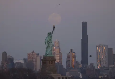 Shutterstock An indistinct moon can be seen behind the Statue of Liberty and the Brooklyn Tower in New York City