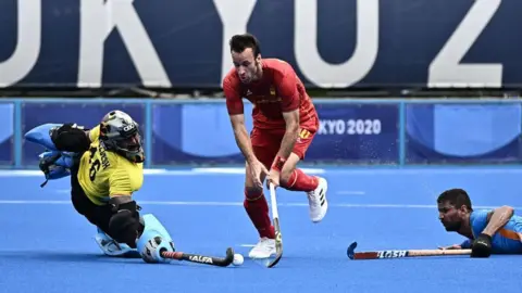 Getty Images Spain's David Alegre (C) dribbles the ball between India's goalkeeper Sreejesh Parattu Raveendran (L) and player Harmanpreet Singh during their men's pool A match of the Tokyo 2020 Olympic Games field hockey competition, at the Oi Hockey Stadium in Tokyo on July 27, 2021. (Photo by JEFF PACHOUD / AFP) (Photo by JEFF PACHOUD/AFP via Getty Images)