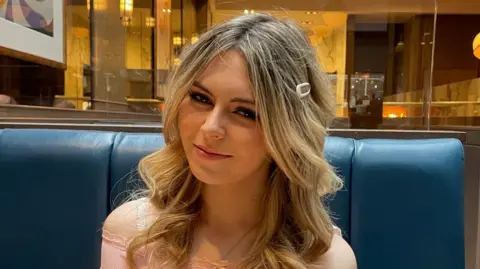 Isla Sneddon, a teenage girl with long blonde hair and wearing a pink top. She is smiling at the camera.