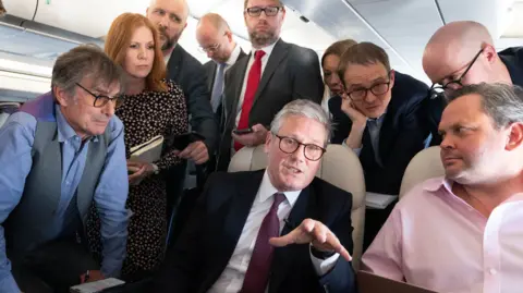 PA Media Sir Keir Starmer on the plane to Washington DC, where he will answer questions from journalists