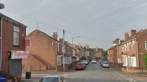 View looking down Highwoods Road in Mexborough - with a corner shop on the left and terraced housing receding into the distance