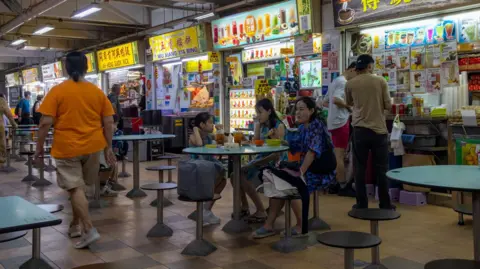 A young girl dining with two women at a table at a hawker centre