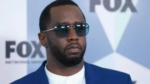 Getty Images Sean "Diddy" Combs poses in a blue jacket and black mirrored sunglasses