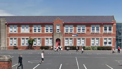 Heathfield Primary - a red brick school building with a playground in front of it