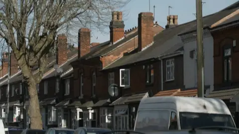 A row of terraced houses in Birmingham with vehicles parked outside.