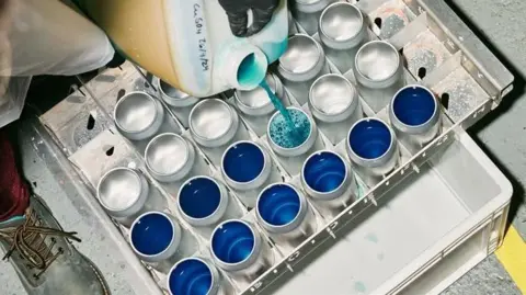 Meadow Cans being filled with a blue liquid