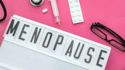 The word menopause on a lightbox surrounded by pills