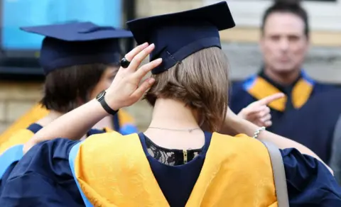 PA Media Anonymous rear shot of graduates wearing graduation robes