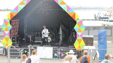 Gig underway at Urdd Eisteddfod in Cardiff Bay over the summer half-term. The band Dienw on stage