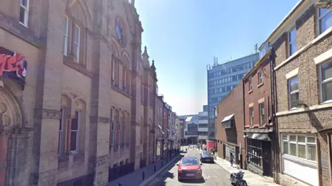 Leazes Park Road in Newcastle City Centre. A typical city street with a row of town buildings with cars parked in it. 
