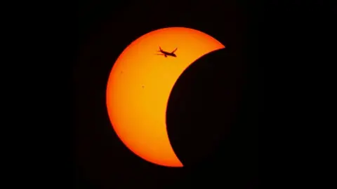 View of the eclipse with a plane in shot