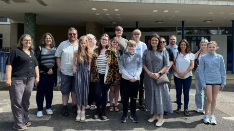 BBC Smiling parents and pupils standing outside Durham County Council's headquarters after the planning permission was approved