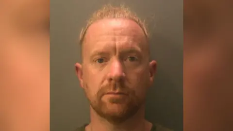 Sussex Police The image shows a police mugshot, head-and-shoulders photograph of a white man with ginger/blonde hair against a plain, neutral-coloured background.