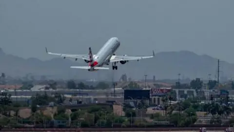 Plane takes off from runway, desert seen in background