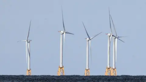 Five wind turbines mounted on yellow metal structures embedded into the sea bed at the Block Island Wind Farm off the coast of Block Island, RI.