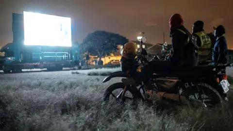 AFP Kenyans on bikes watch a football match on a giant screen in Nairobi - Tuesday 26 June 2018