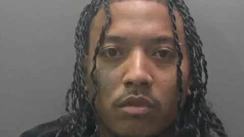 Cambridgeshire Police Custody image of Hamilton, a man, with curly black long hair.