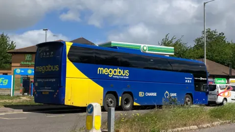 A blue bus parked on the side of a road.