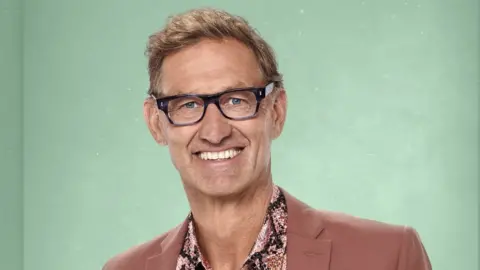 PA Media Tony Adams poses for the camera in a pink blazer