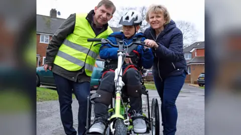 Mikey on a specially designed bike with his parents