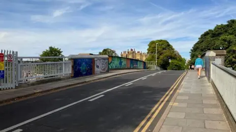 Local Democracy Reporting Service The Mill Road bridge over the railway in Cambridge with people walking along one of its pavements