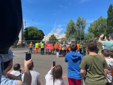 Crowds of adults and childre watch the towers come down