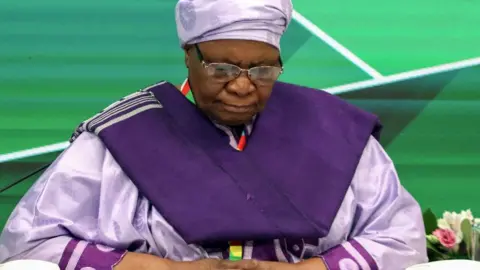 LightRocket/Getty Images Netumbo Nandi-Ndaitwah with head bowed wearing a purple outfit against a green background.