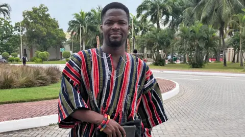 Andrews Tetteh Zutah in a stripped red, khaki and black fugu in Accra.