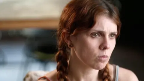 Young woman with reddish-brown hair in plaits
