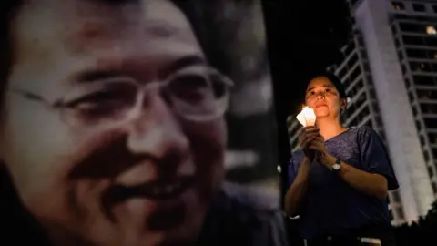 Getty Images A woman holds a candle as she attends a vigil for terminally-ill Nobel laureate Liu Xiaobo (pictured on banner) in Hong Kong on June 29, 2017