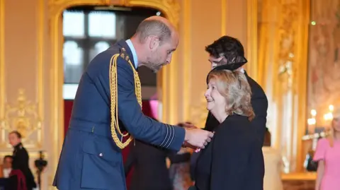 PA Media Wendy Daunt receiving her OBE medal from Prince William inside Windsor Castle.