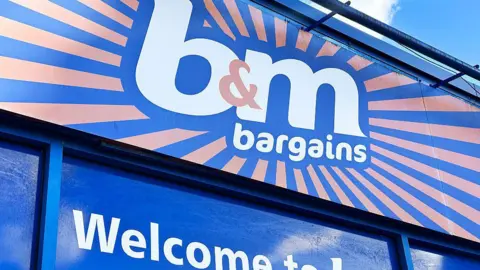The top of a B&M shop with showing a shop logo the white writing has a dark blue and orange background. 