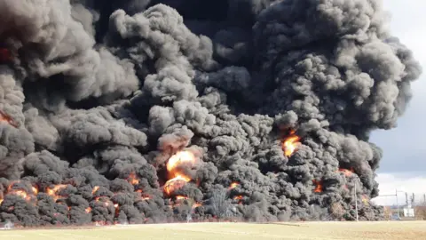 Hasiči Olomouc A large fire is visible along a rail line on the other side of a field