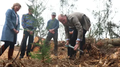 PA Media Prince William plants a tree watched by an appreciate group of people 