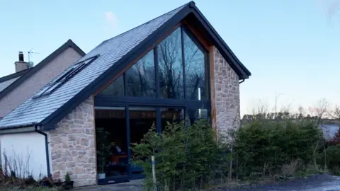 Cyngor Gwynedd Planning Documents The outside of a property which has very large dark windows at the front, a slanted roof and stone walls