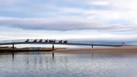 RAF Lossiemouth RAF personnel in camouflage carrying Christmas trees over a bridge across water, and a cloudy skyline.